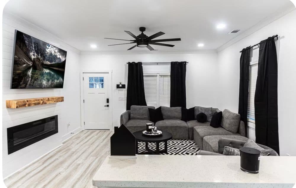 Modern living room with gray sectional sofa, large TV, and stylish decor in a cozy atmosphere.
